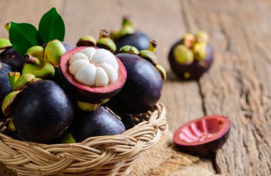 Bambu sepetinde taze Mangosteen ve eski ahşap arka planda. Mangosteen, 