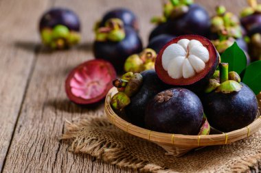 Bambu sepetinde taze Mangosteen ve eski ahşap arka planda. Mangosteen, 