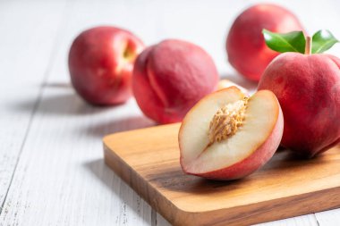 Tahta tabakta taze şeftali ve beyaz arka plan. Şeftaliler yaygın olarak taze yenir ve ayrıca turtalar, turtalar ve zengin A vitamini ile pişirilir..