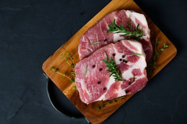 Biberiyeli domuz eti parçaları ve ahşap tabakta kekik yaprakları, çiğ taze domuz eti bifteği konsepti.