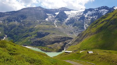 Karla kaplı yeşil dağların manzarası ve aşağıdaki göl.