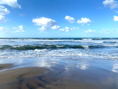 Kumda beyaz bulutların yansıması olan deniz kıyısı.