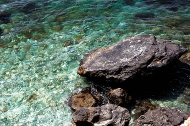 Gök mavisi deniz suyunda büyük kahverengi bir taş.