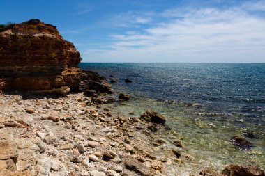 Uçurumun manzarası, taşlardan ve denizden oluşan boş bir plaj.