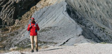 Sırt çantalı bir erkek turist dağlardan aşağı iniyor, panorama. Dağların arka planında bir gezgin. Dağların arkasında sırt çantalı bir turist. Boşluğu kopyala