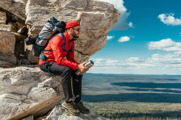 男の観光客が山を登るのは難しい後に休んでいる ロッキー山脈の間の旅行者 男は岩の間にリュックを持つ旅行者です 山の中でバックパッキング スペースのコピー — ストック写真