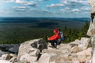 Bir erkek turist dağa tırmandıktan sonra dinleniyor. Rocky Dağları 'nın arasında bir gezgin. Bir adam kayaların arasında sırt çantalı bir gezgindir. Sırt çantasıyla dağlarda. Boşluğu kopyala