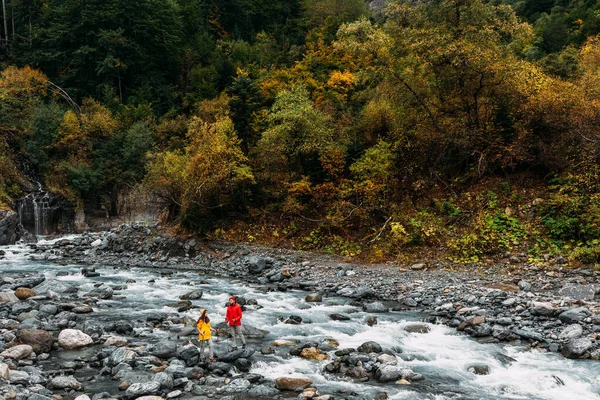 秋には数人の観光客が川沿いを歩く 自然の中で活発な休息 アクティブなカップルがハイキングに従事しています 若いカップルが追跡に従事している スペースのコピー — ストック写真