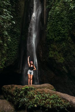 Bali Endonezya adasındaki şelalede güzel bir kız. Şelaledeki seksi kadın. Bikinili genç ve güzel bir kız şelalede banyo yapıyor. Şelalede poz veren güzel bir kadın.