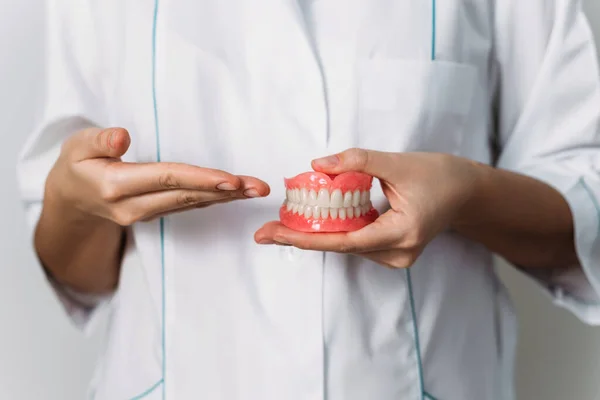 歯医者は彼の手に入れ歯を持っている 医師の手の中に歯科補綴物を閉じる 完全な入れ歯の正面図 歯の概念写真 歯医者だよ — ストック写真