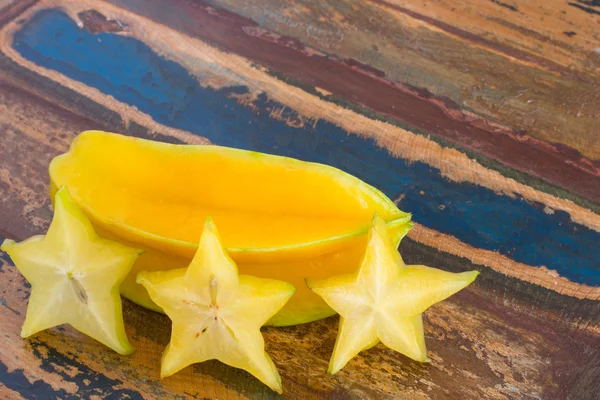 Carambola e fatias em mesa de madeira — Fotografia de Stock