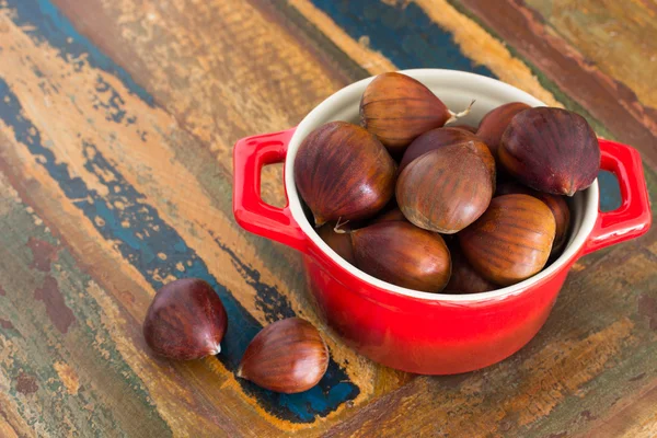 Kastanje in rode kom op houten tafel. selectieve aandacht — Stockfoto