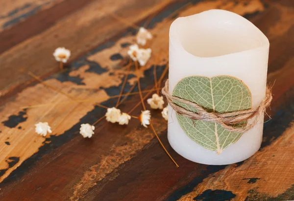 Декоративная свеча с сушеными листьями и цветами андо на деревянном столе — стоковое фото