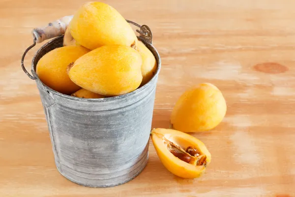 Loquat fruit  in bucket on wooden table — Stock Photo, Image