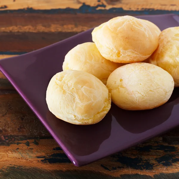 Pane di formaggio brasiliano (pao de queijo) su piatto viola — Foto Stock