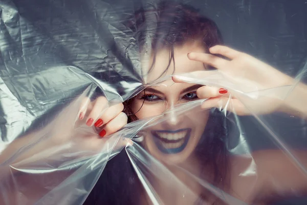 Woman with creative eye makeup peering cellophane — Stock Photo, Image