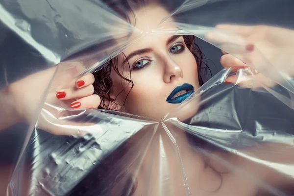 Woman with creative eye makeup peering cellophane — Stock Photo, Image