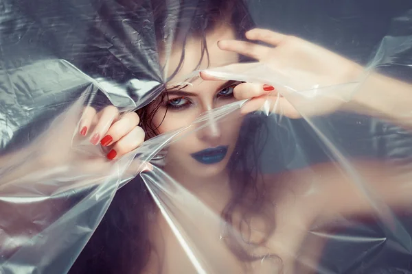 Woman with creative eye makeup peering cellophane — Stock Photo, Image