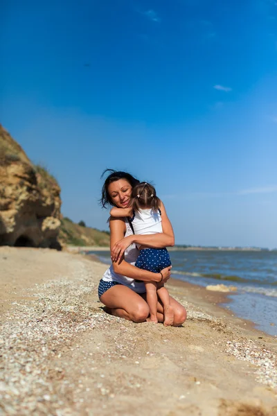 Ragazza con madre sulla spiaggia in riva al mare — Foto Stock