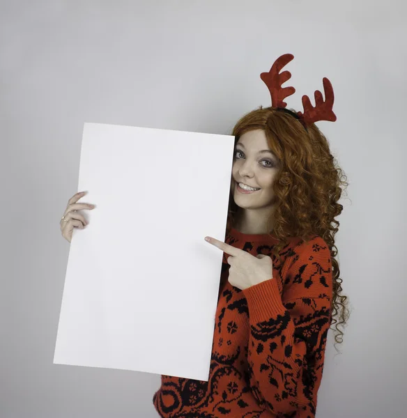 Young woman wearing red antlers and holding blank sign — Stock Photo, Image
