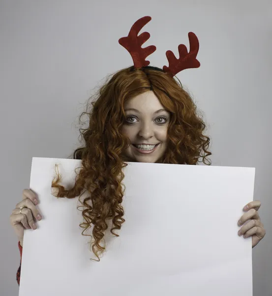 Young woman wearing red antlers and holding blank sign — Stock Photo, Image