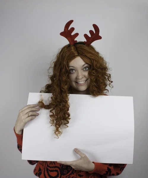 Pretty young woman wearing antlers and holding blank sign — Stock Photo, Image