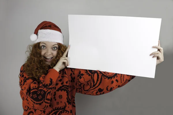 Pretty young woman wearing Santa hat and holding blank sign — Stock Photo, Image