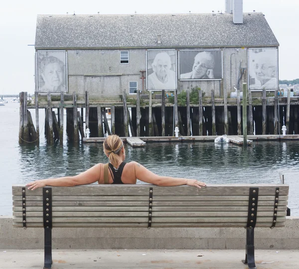Žena sedí na lavičce, fishermans wharf, provinetown, ma — Stock fotografie
