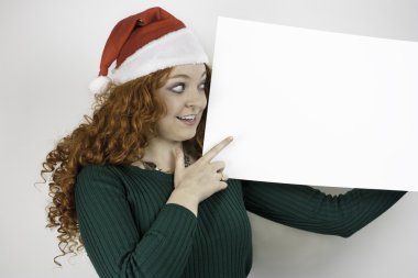 Noel Baba şapkası giyen ve boş işaret tutan genç ve güzel kadın