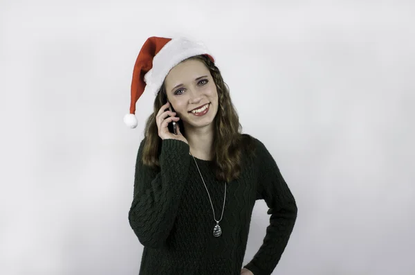 Pretty young woman wearing Santa hat and talking on cell phone — Stock Photo, Image