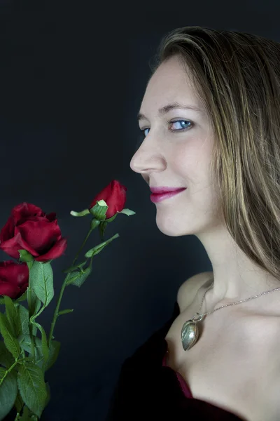 Hübsche junge Frau mit roten Rosen — Stockfoto