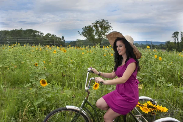 Vrouw op fiets met zonnebloemen — Stockfoto