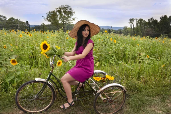 Kvinna på cykel med solrosor — Stockfoto