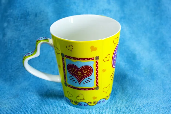 Красочная чашка с фоном из цветной ткани — стоковое фото