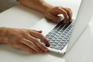 Dizüstü bilgisayarda çalışan bir adam, elleri kapalı.