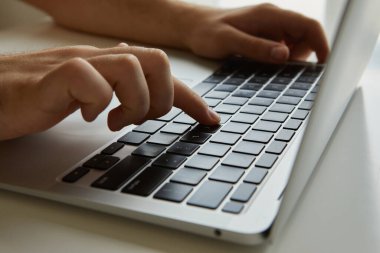 Dizüstü bilgisayarda çalışan bir adam, elleri kapalı.