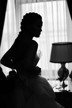 Genç gelin düğünden önce pencerede giyiniyor.