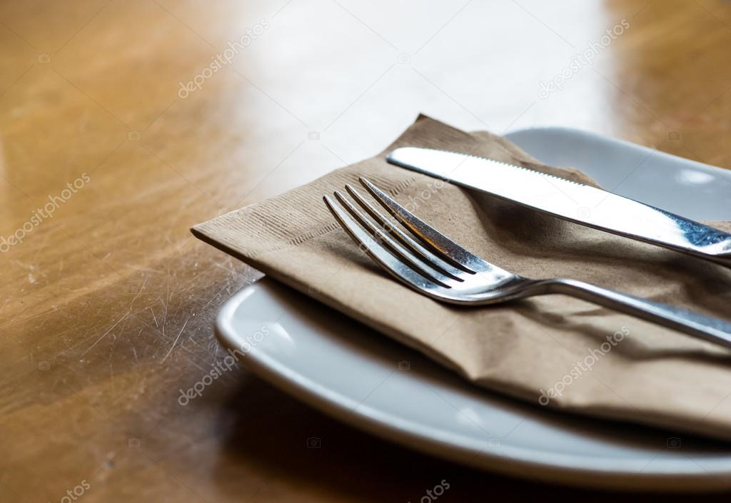 Knife and fork on plate with brown napkin