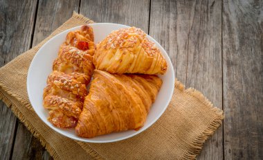 French breakfast croissant in a white disk and hemp sack on the dark wooden table background with copy space for your text.