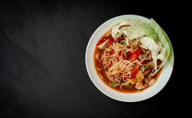 Som Tam Thai, green papaya Salad Thai Food Style on the dark black kitchen table background. Thai Food Concept. Top View with copy space
