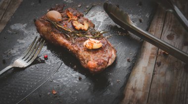 medium rare steak with Himalayan Pink salt, rosemary leaf herbs garlic, and spices red black, and white pepper on a slate plate for steak menu lunch and dinner concept