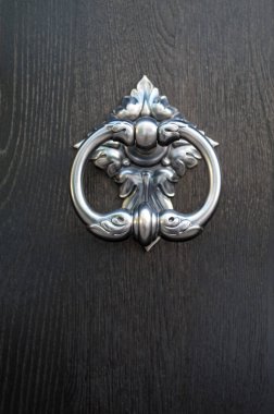 New decorative round metal door knocker on wood door closeu