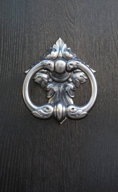 New decorative round metal door knocker on wood door closeu