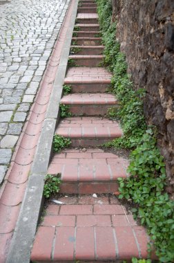 Old steep paved street with steps and an open drainage channe