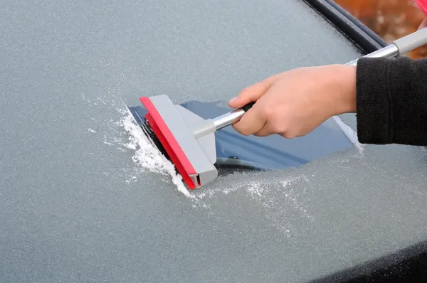 Winter driving - woman scraping ice from a windshield — Stock Photo, Image
