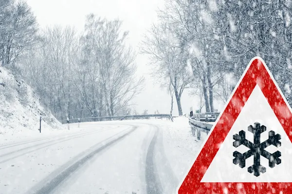 Winter driving - snowfall on a country road with warning sign — Stock Photo, Image