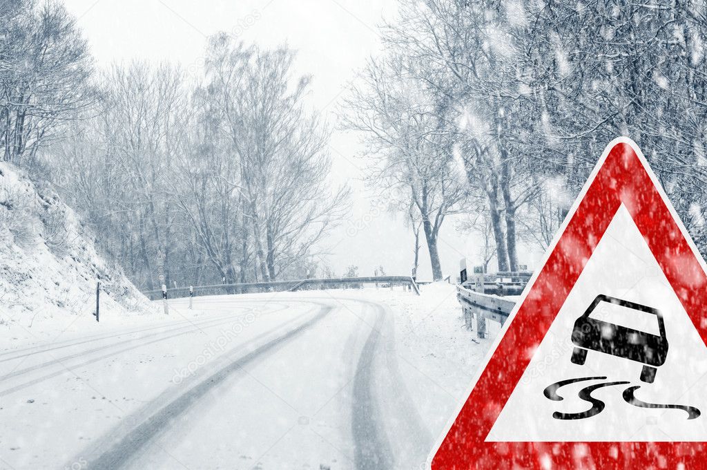 Winter driving - snowfall on a country road with warning sign