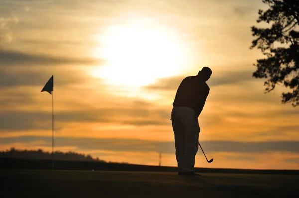 Golfer bei grün beleuchtetem Sonnenuntergang lizenzfreie Stockfotos