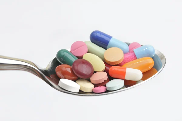 Mnoho různých barevných tablety a prášky na lžíci — Stock fotografie
