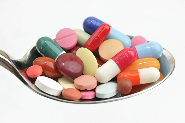Viele verschiedene farbige Tabletten und Pillen auf einem Löffel — Stockfoto